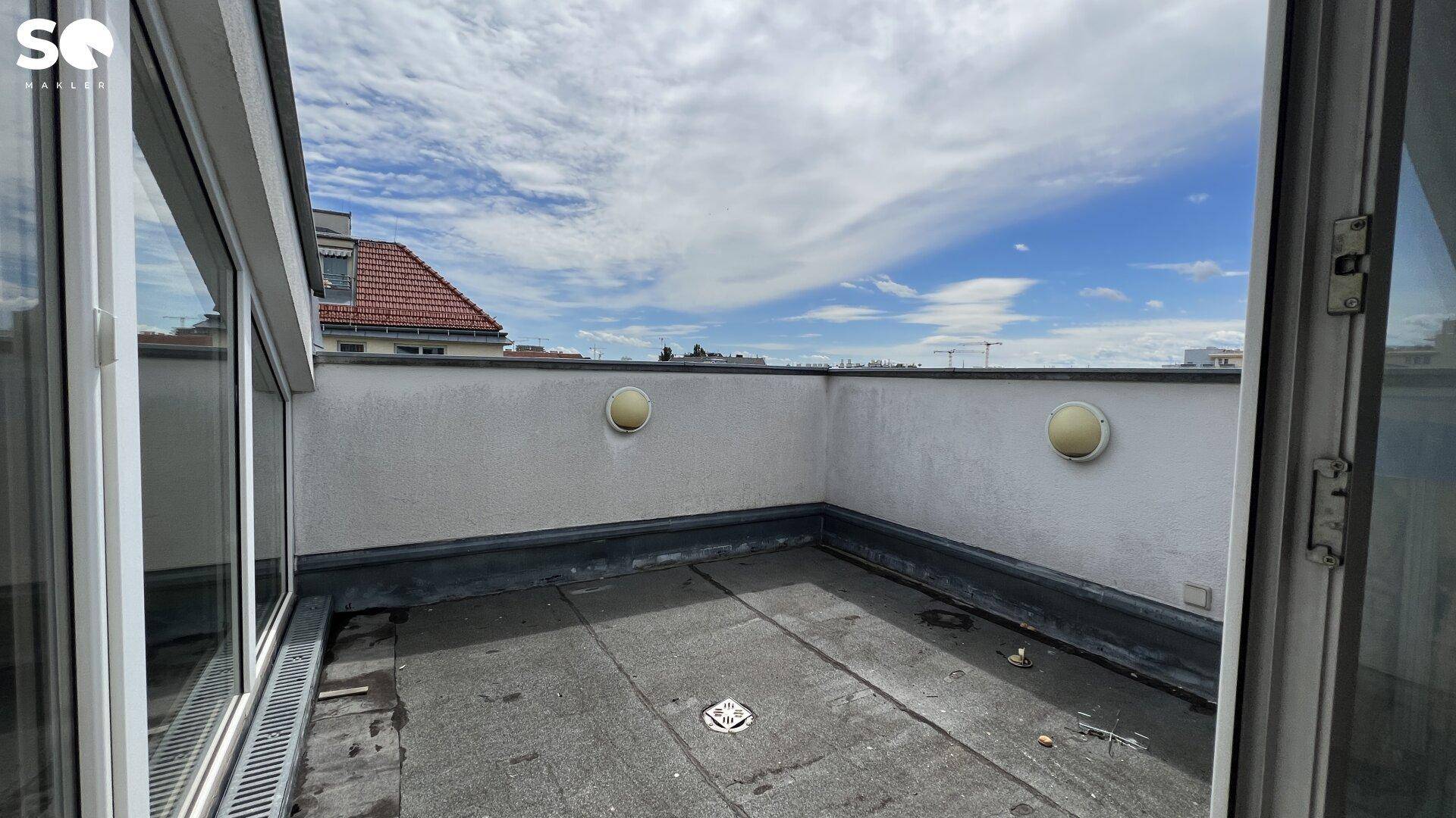 Kleine Dachterrasse mit niedriger Brüstung und Blick auf die umliegenden Gebäude.