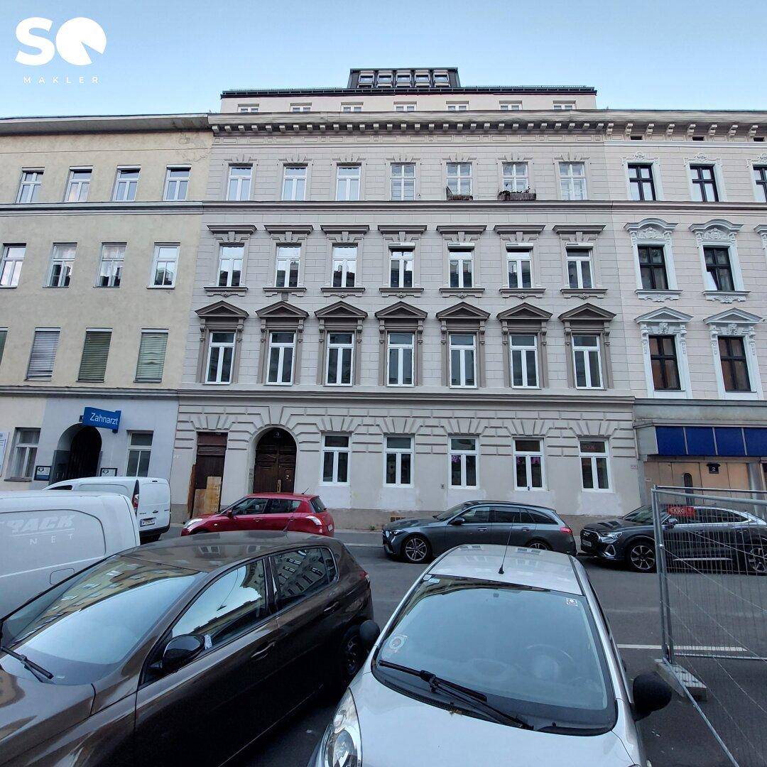 Ansicht der historischen Gebäudefassade von der Straße mit parkenden Autos davor.