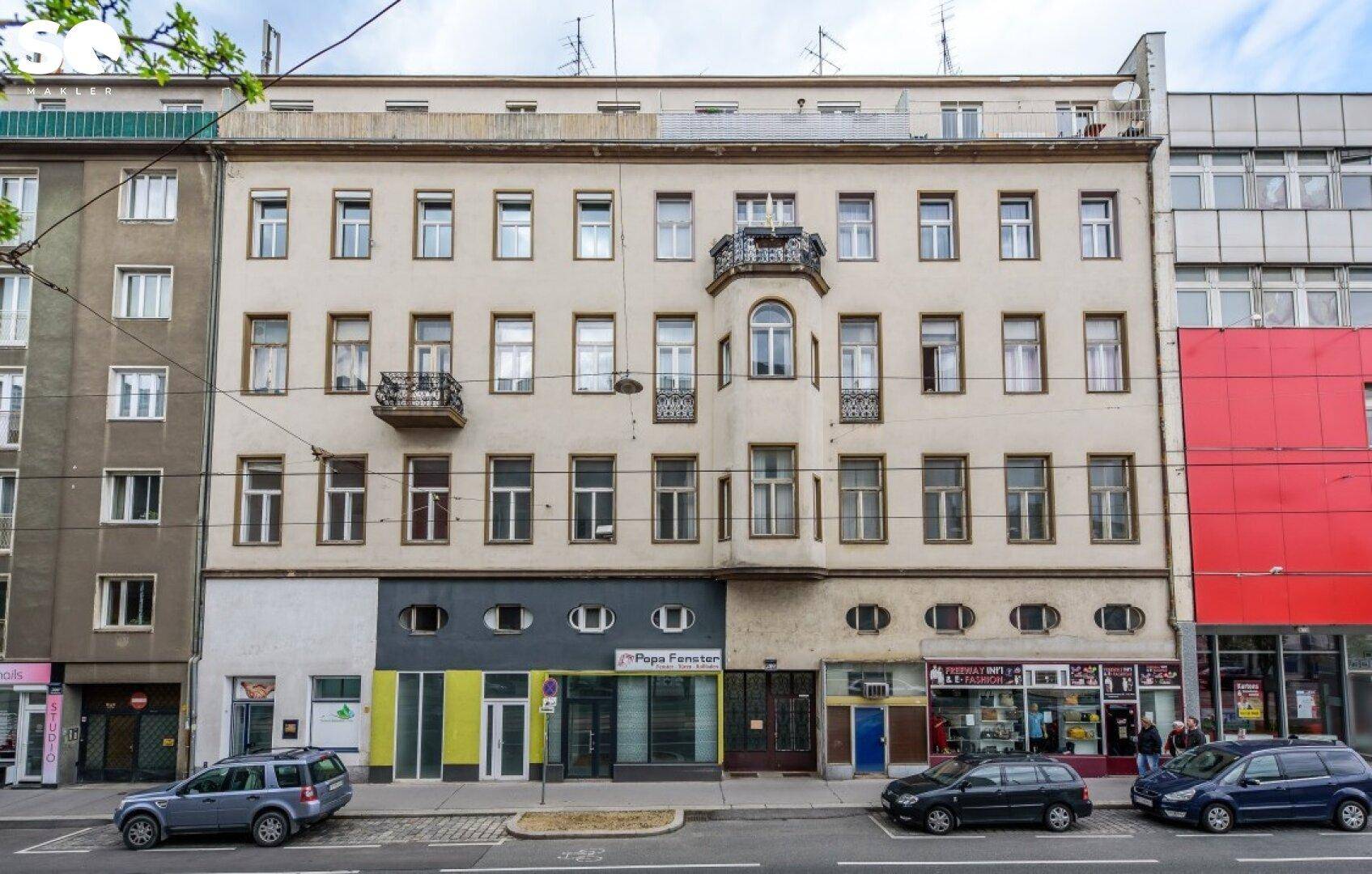 Historisches Mehrfamilienhaus mit klassischer Fassade, Balkonen und Geschäften im Erdgeschoss.