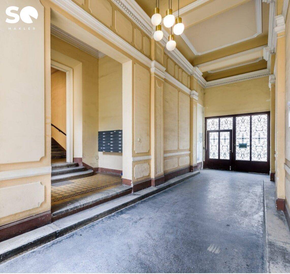 Repräsentativer Eingangsbereich eines Altbaus mit hohen Decken und dekorativen Elementen.