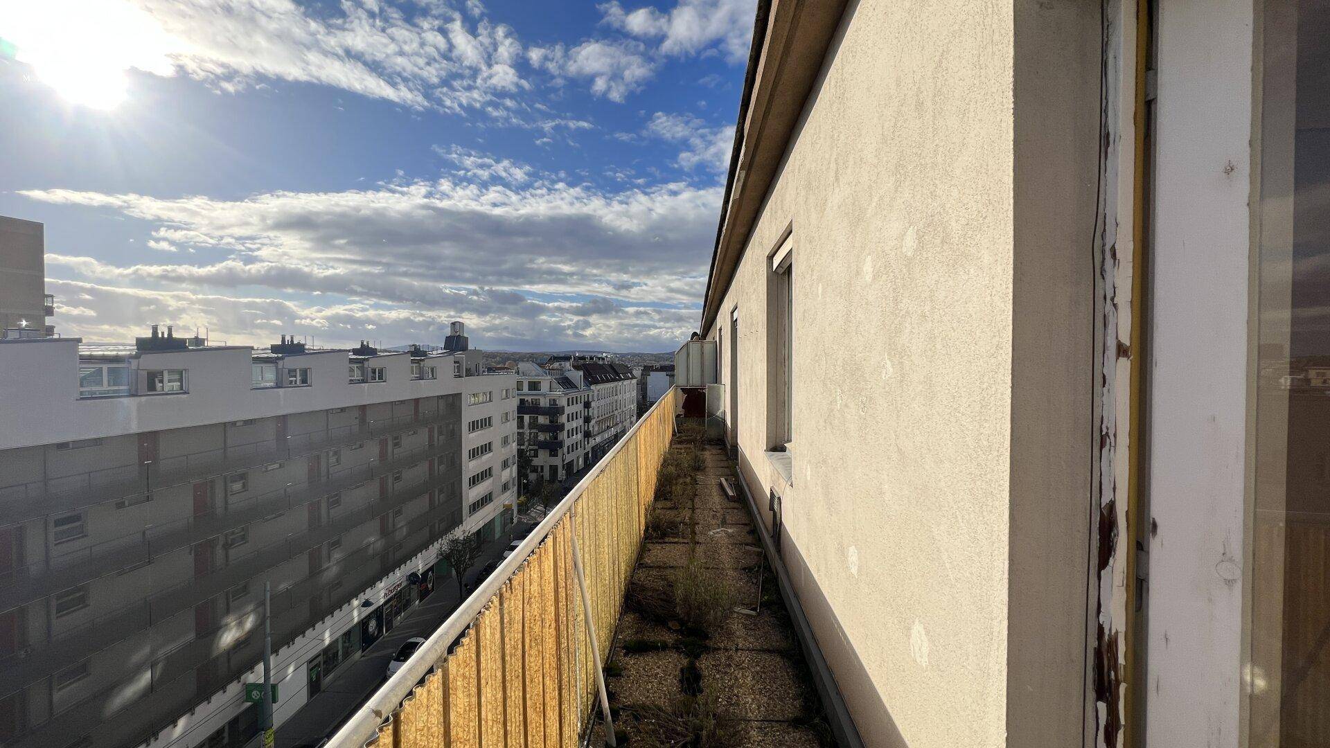 Langer, schmaler Balkon mit Blick auf die Stadt und Renovierungsbedarf.