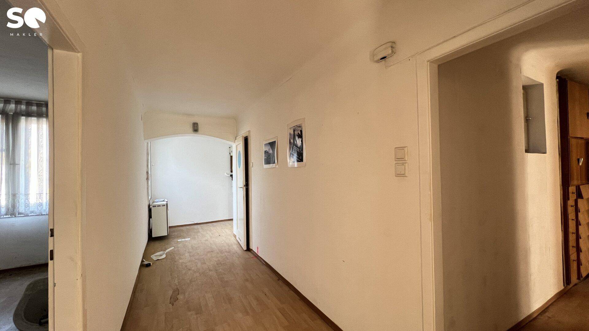 Langer Flur mit Holzboden und Zugang zu verschiedenen Räumen.