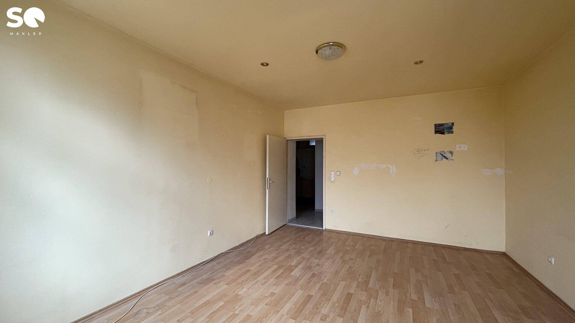Unmöbliertes Zimmer mit gelblichen Wänden und Holzboden, bereit für neue Bewohner.