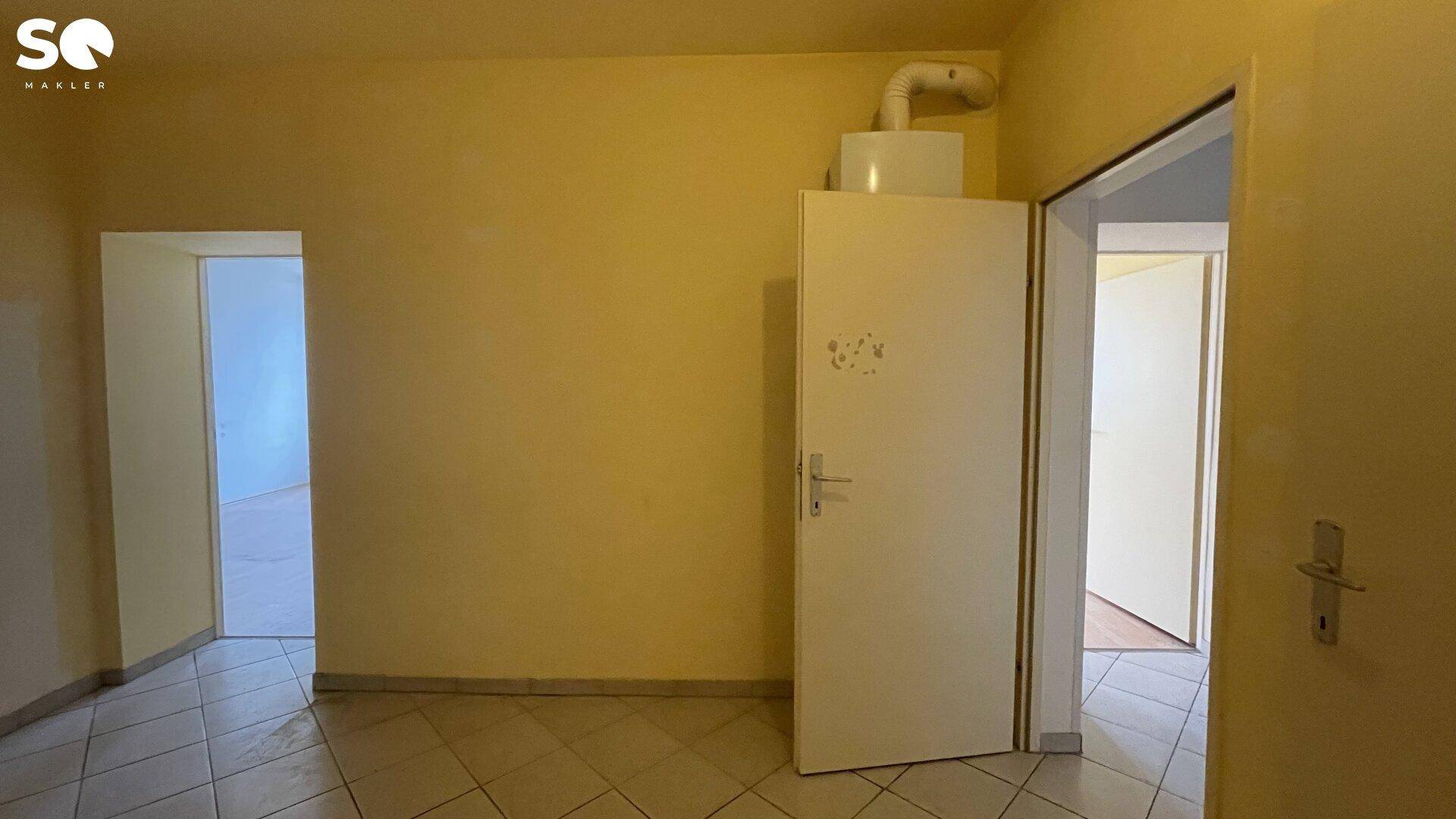 Flur oder Hauswirtschaftsraum mit Fliesenboden und einem Warmwasserbereiter an der Wand.