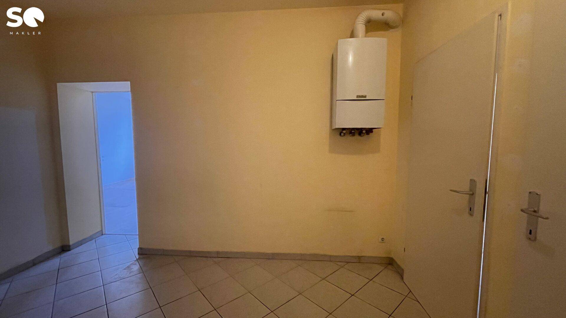 Flur oder Hauswirtschaftsraum mit Fliesenboden und einem Warmwasserbereiter an der Wand.