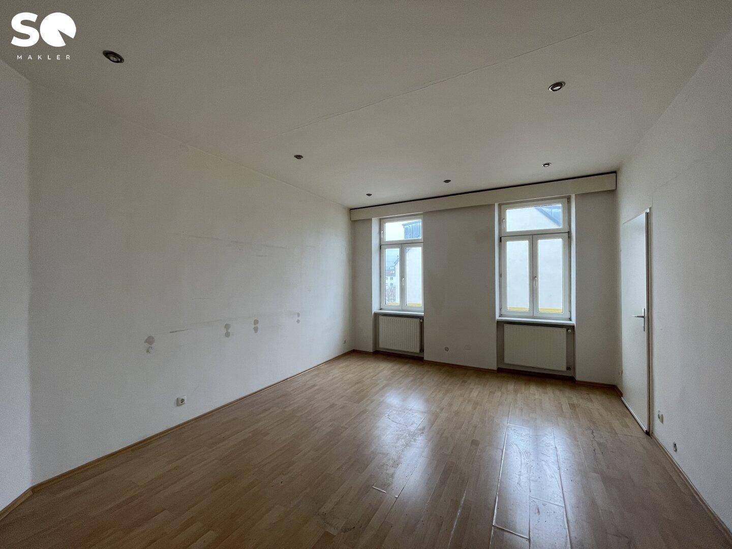 Renoviertes Zimmer mit weiß gestrichenen Wänden und glänzendem Holzfußboden.