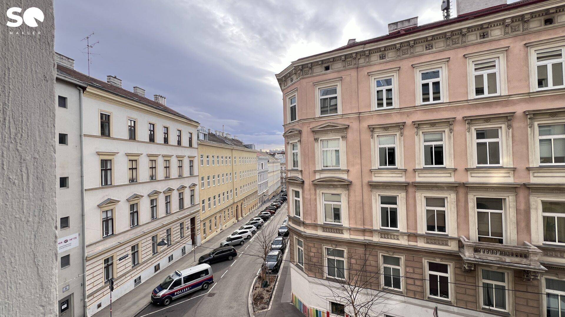 Straßenansicht mit historischen Gebäuden und einem Polizeifahrzeug auf der Straße.