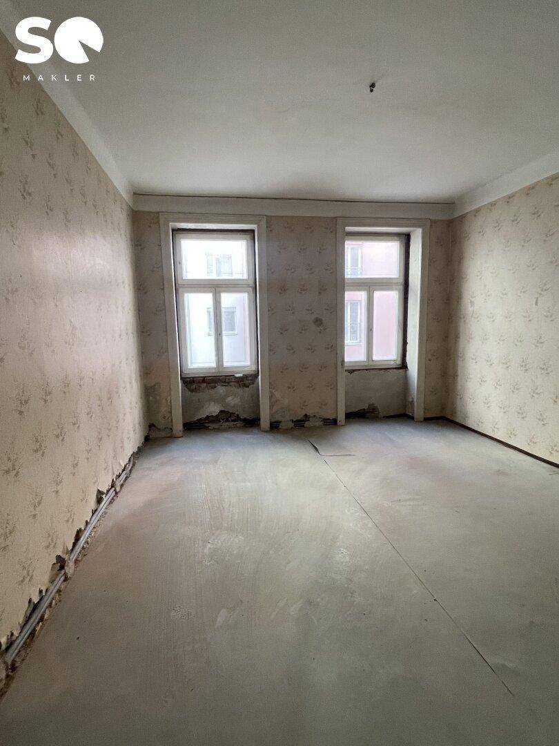 Renovierungsbedürftiges Zimmer mit freigelegten Wänden und Rohfußboden, bereit für den Ausbau.