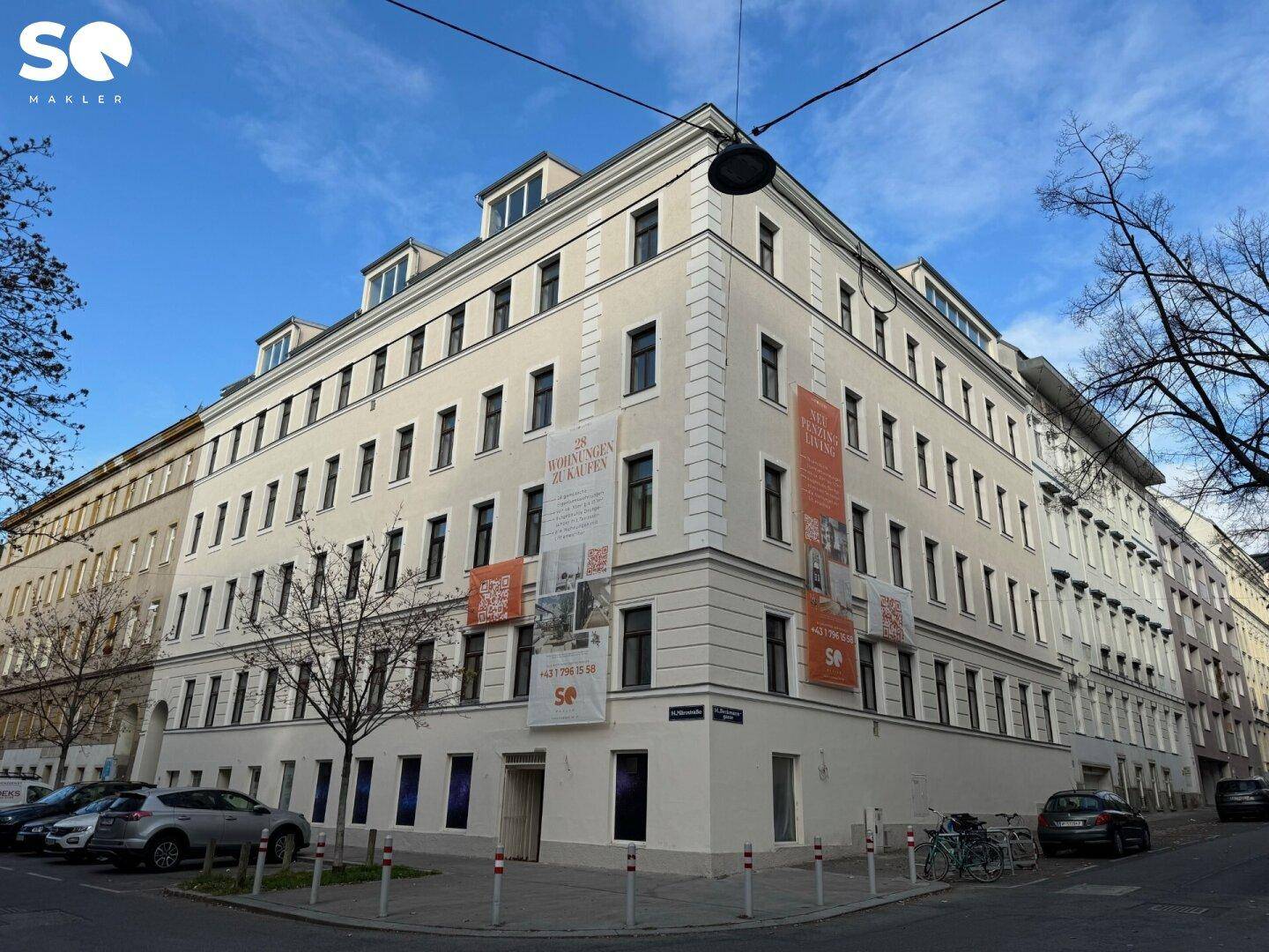 Eckansicht eines frisch renovierten Wohngebäudes mit moderner Architektur und Mansarddach in der Stadt.