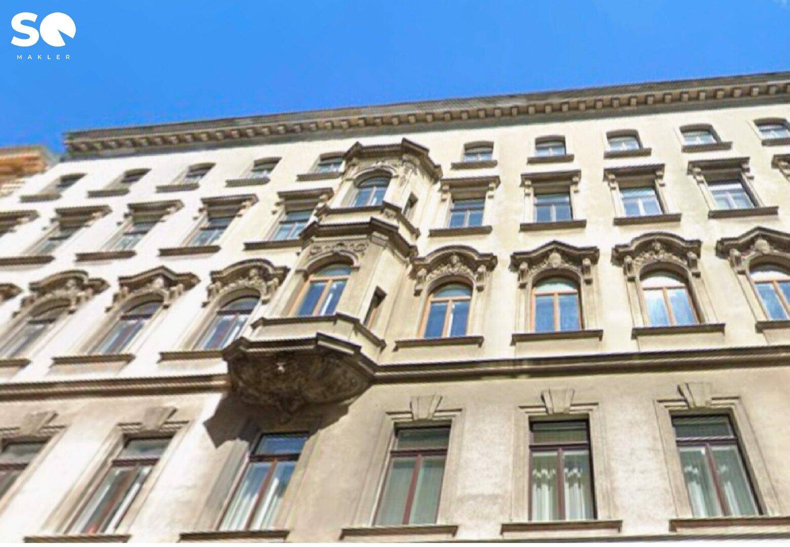 Historische Fassade eines Altbaus mit dekorativen Fenstern und Erker.