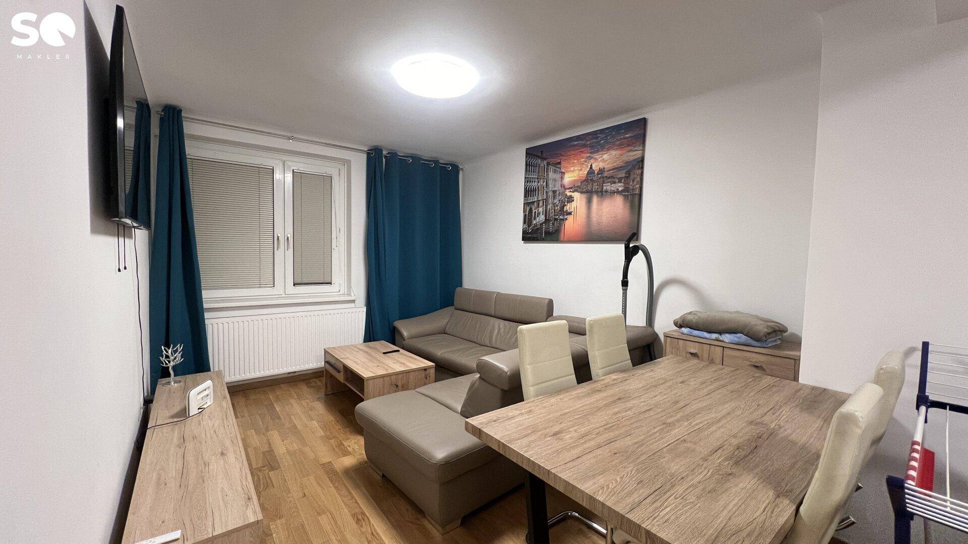 Gemütlicher Wohn- und Essbereich mit beigem Sofa, Holztisch und modernem Wandbild.