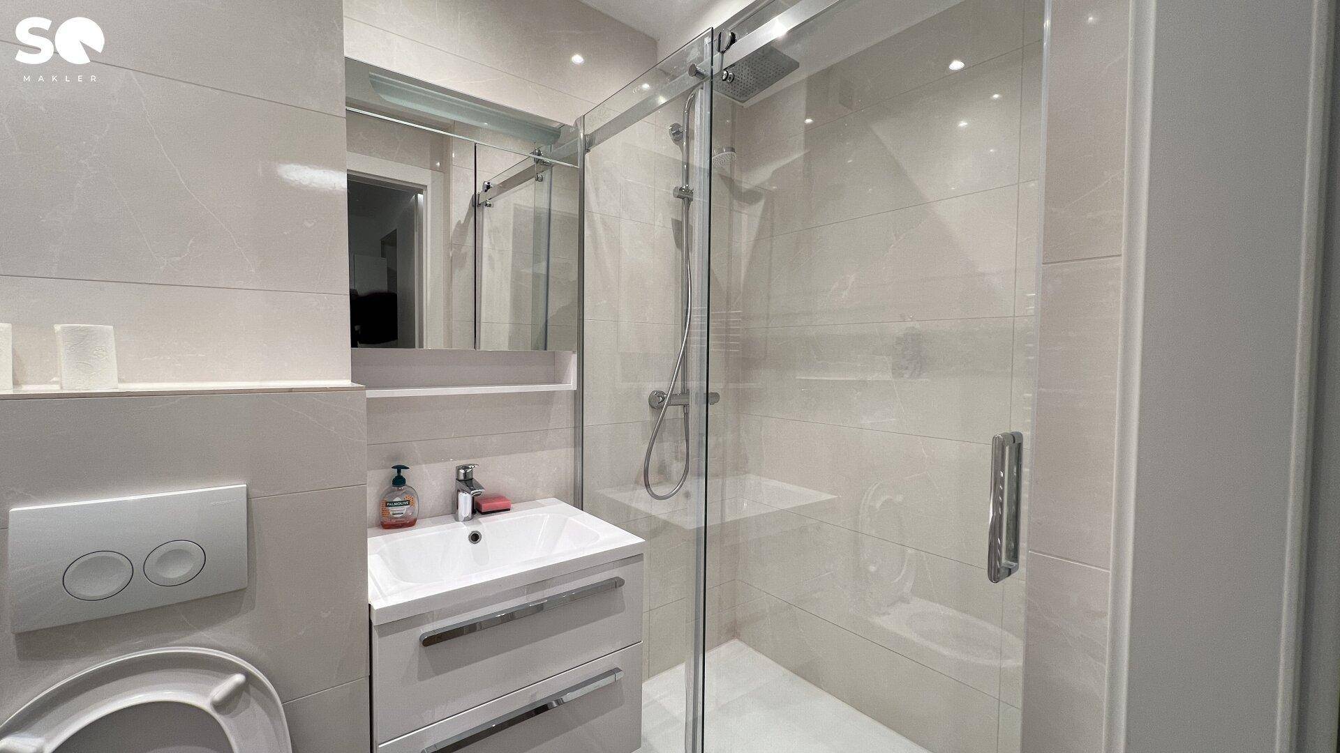 Modernes Badezimmer mit begehbarer Dusche, Wand-WC und hellen Fliesen.