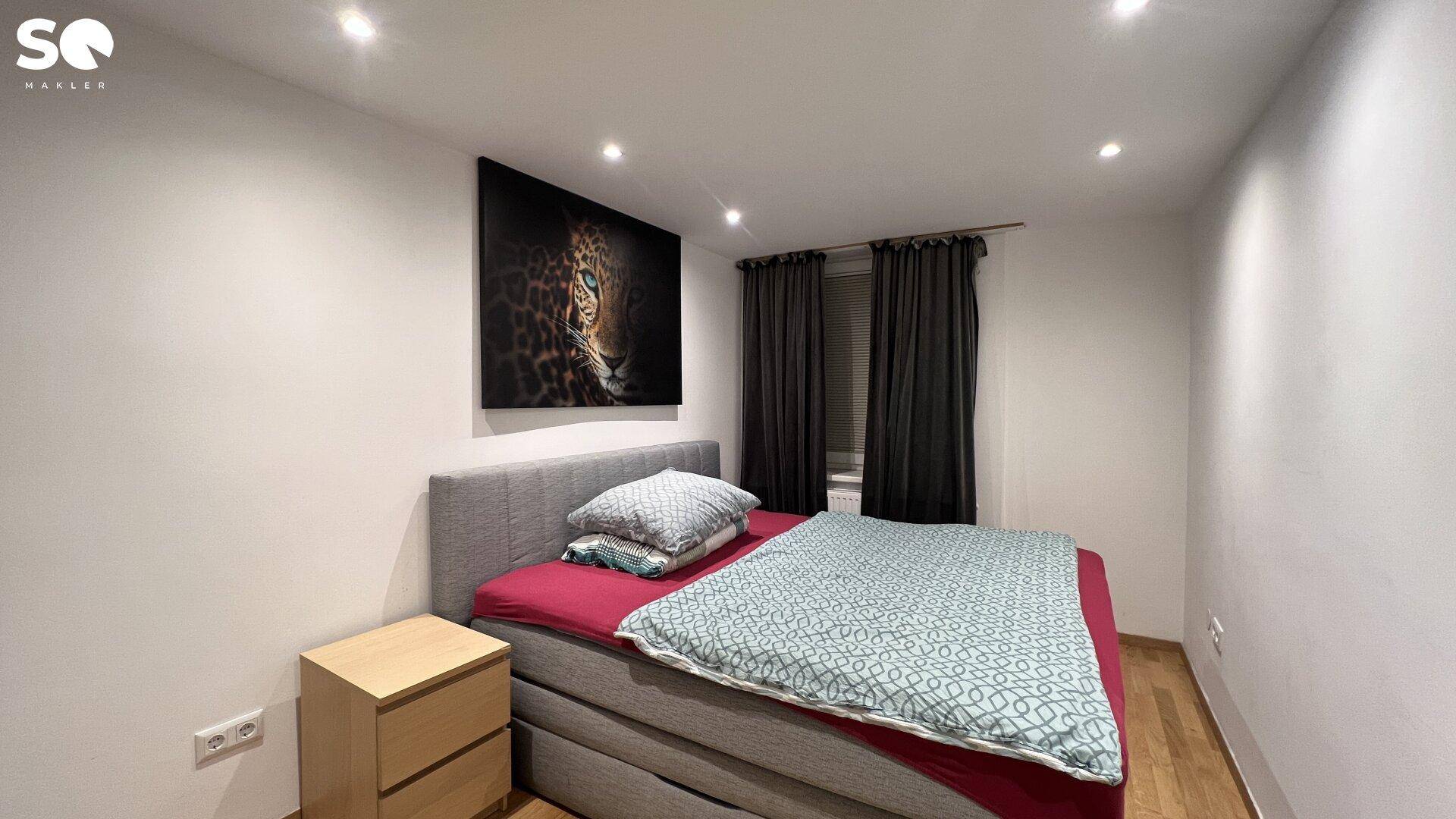 Schlafzimmer mit Doppelbett, Nachttisch und dunklen Vorhängen für erholsamen Schlaf.