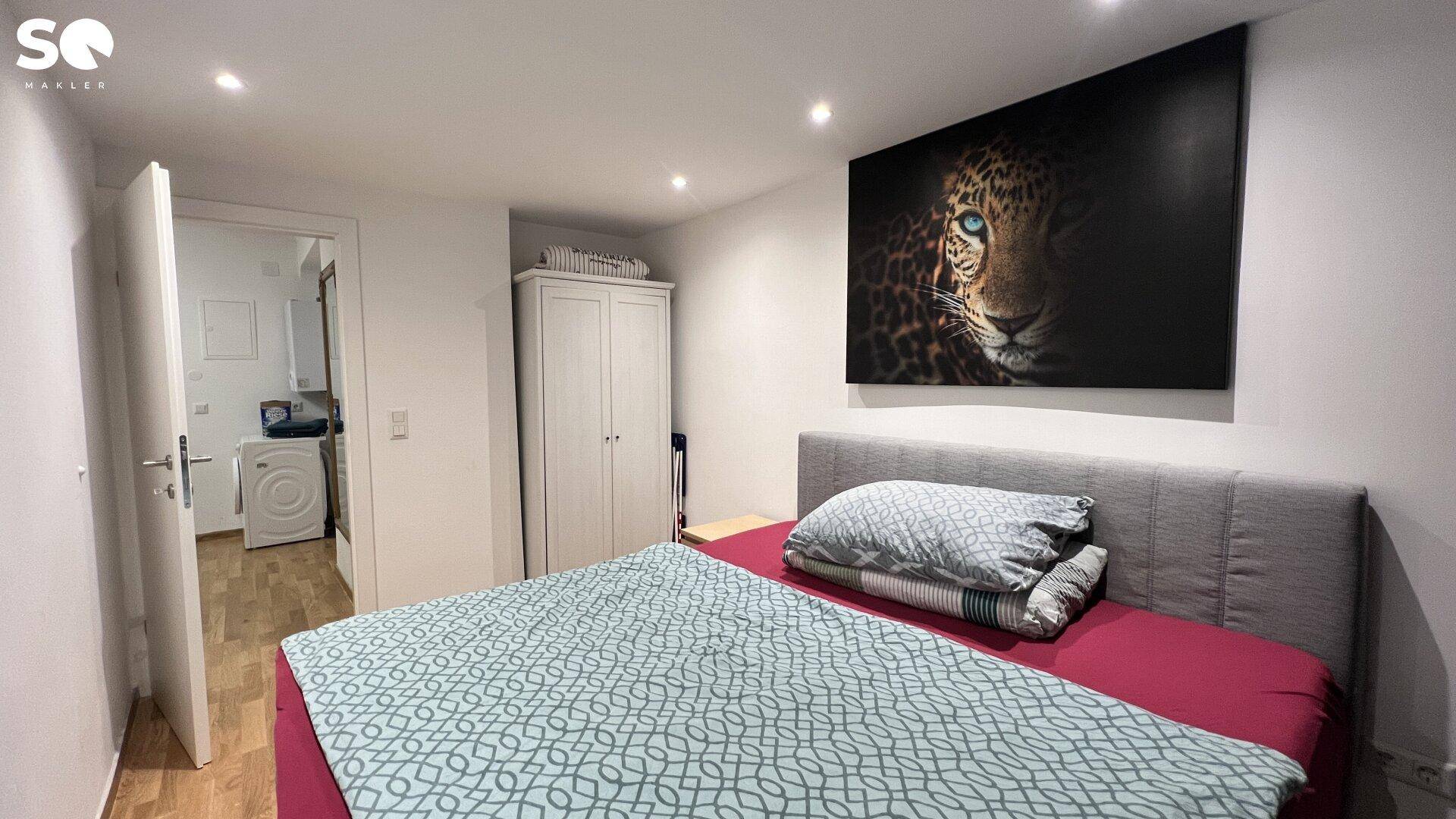 Schlafzimmer mit Kleiderschrank und Zugang zu einem angrenzenden Hauswirtschaftsraum.