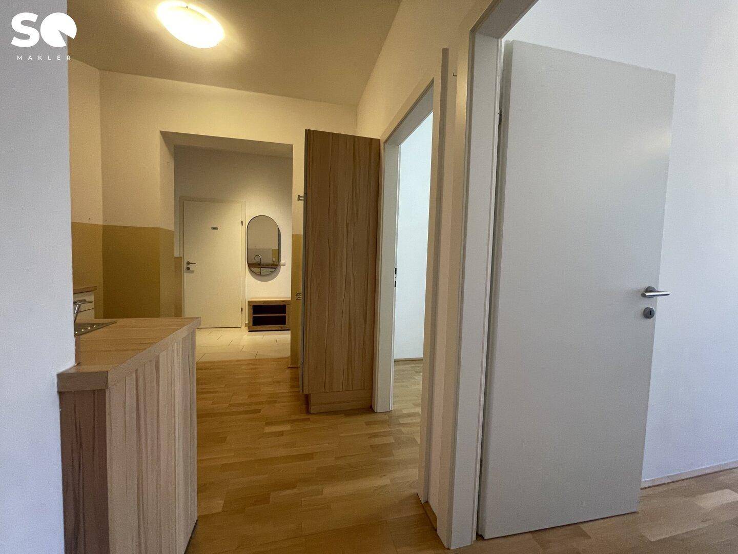 Heller Flur mit Holzboden und Zugang zu verschiedenen Zimmern der Wohnung.