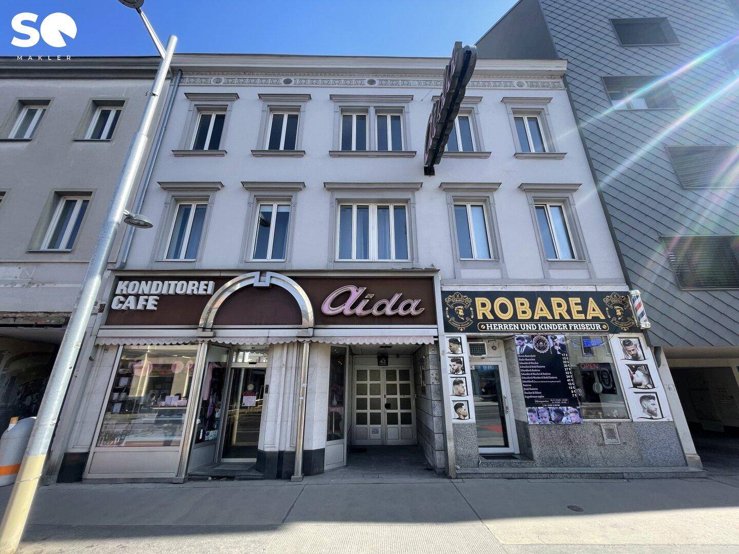 Fassade eines Geschäftsgebäudes mit Konditorei und Friseursalon im Erdgeschoss.