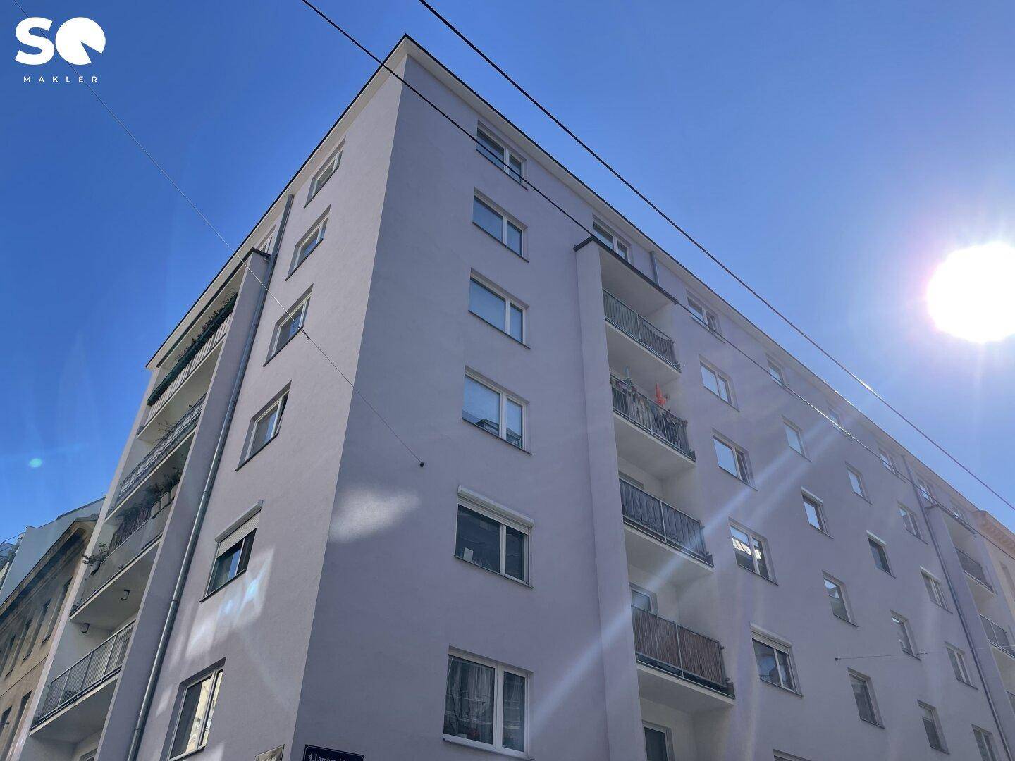Moderne Fassade eines Mehrfamilienhauses mit Balkonen unter blauem Himmel.