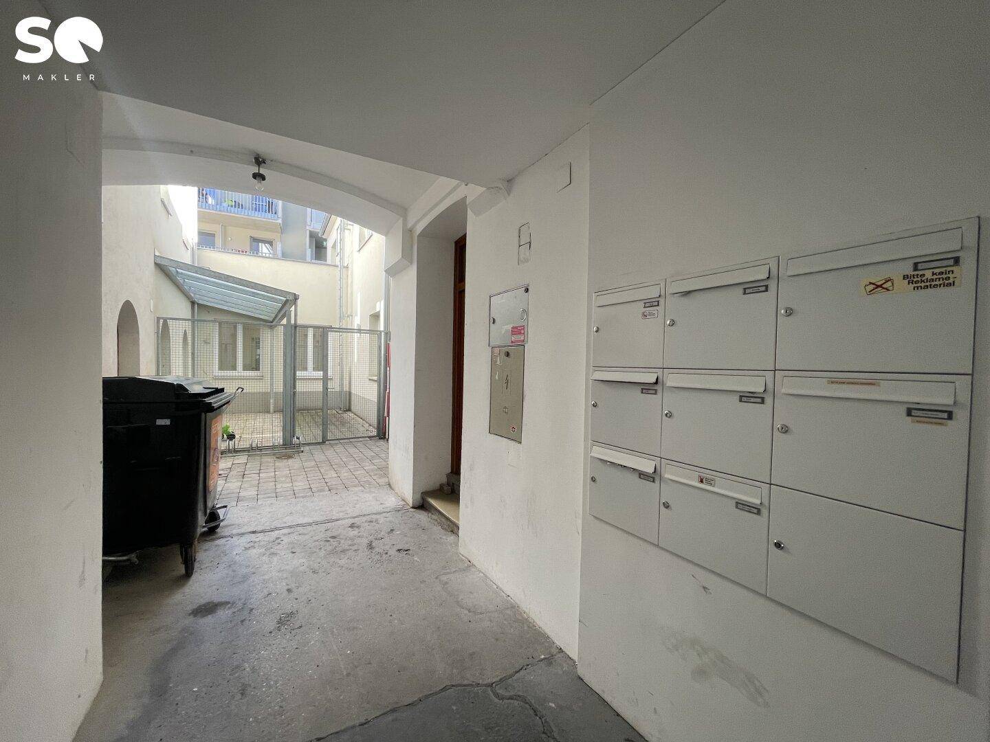 Eingangsbereich mit Briefkästen an der Wand und Durchgang zu einem Innenhof.