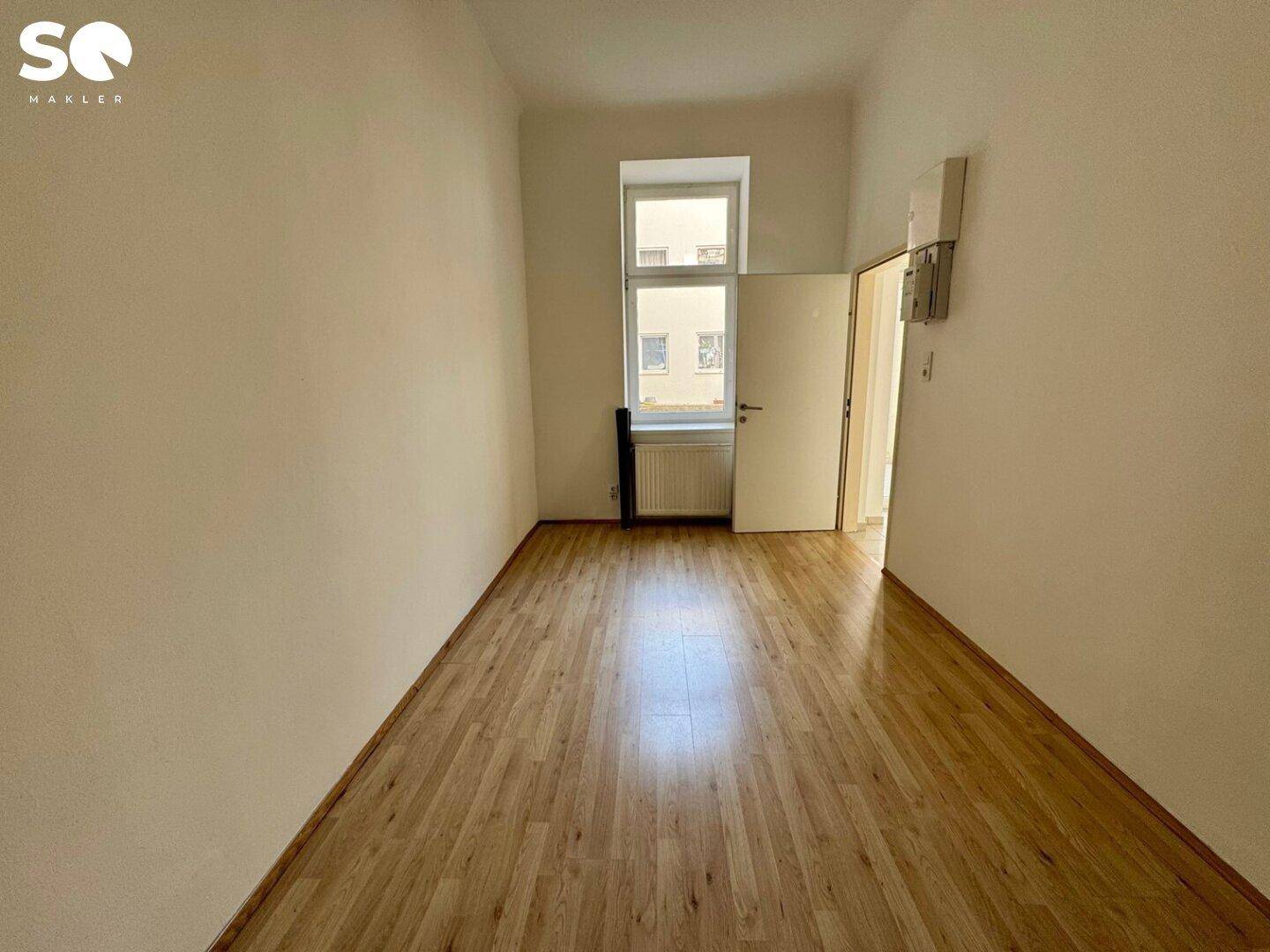 Helles Zimmer mit Holzfußboden und einem Fenster, bietet vielseitige Nutzungsmöglichkeiten.