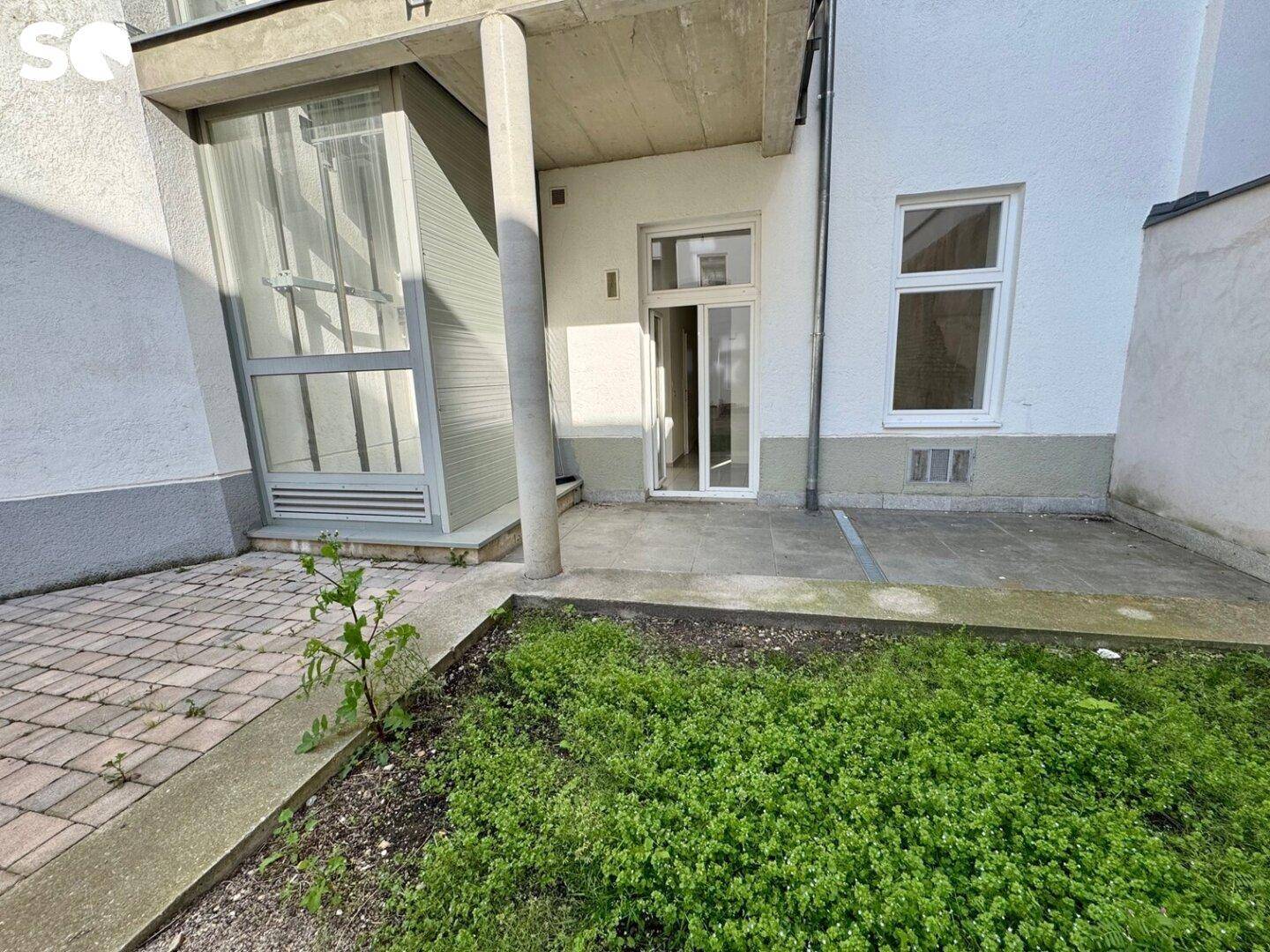 Kleiner Gartenbereich mit gepflasterter Fläche und direktem Zugang zum Gebäude.