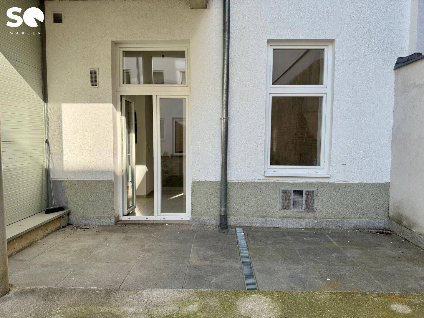 Gepflasterte Terrasse direkt am Gebäude mit Zugang zu den Innenräumen.