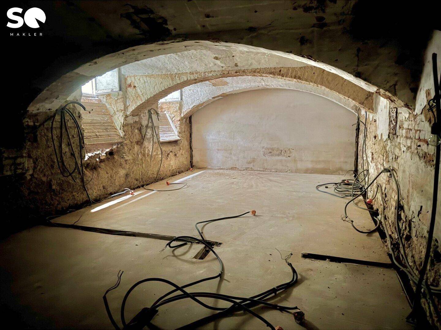 Historischer Gewölbekeller im Rohzustand mit freiliegenden Ziegeln und Verkabelung.