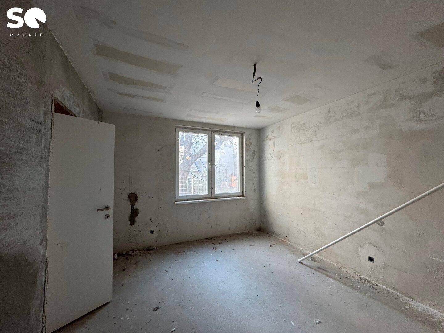 Rohbauzimmer mit Fenster und ungestrichenen Wänden, ideal für individuelle Gestaltung.