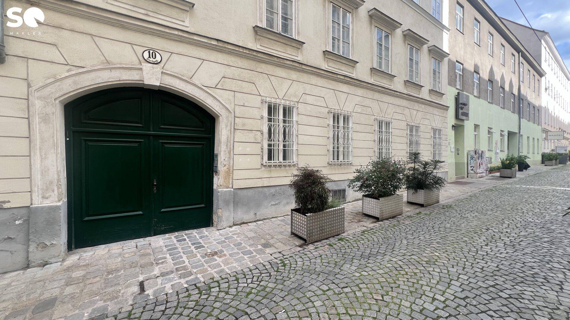 Historische Fassade des Gebäudes an einer gepflasterten Straße mit dekorativen Fenstern.