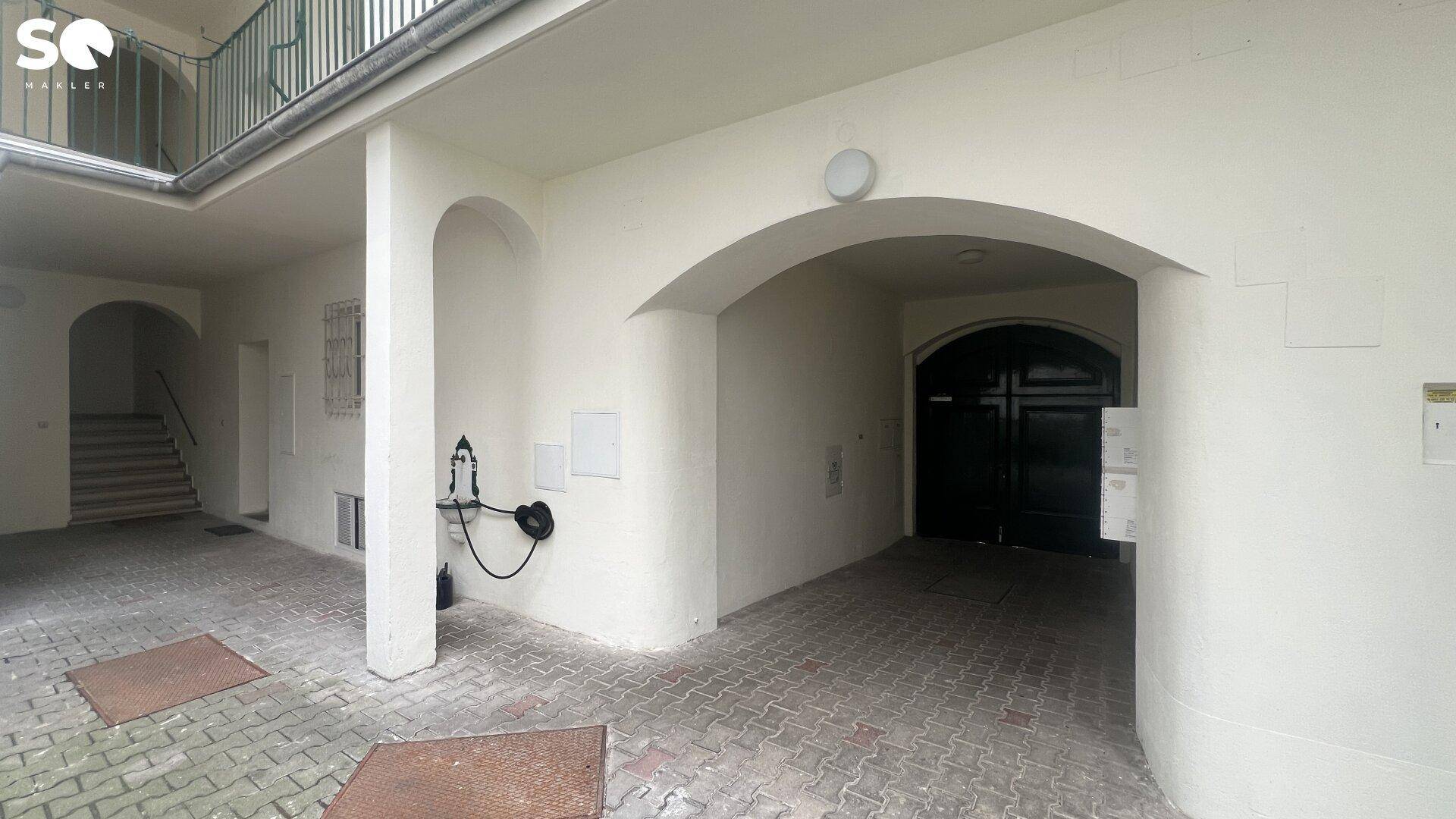 Historischer Innenhof mit Arkaden und Treppenaufgang, der den Charme des Gebäudes unterstreicht.