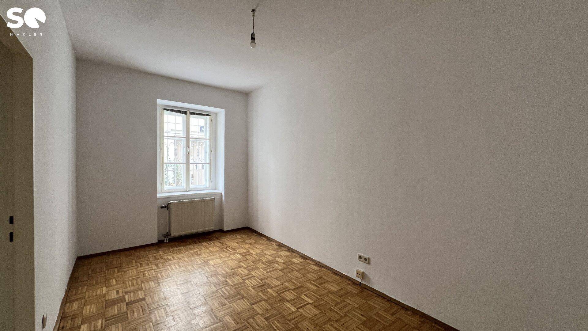 Ruhiges Zimmer mit Parkettboden und einem Fenster, ideal als Schlaf- oder Arbeitszimmer.