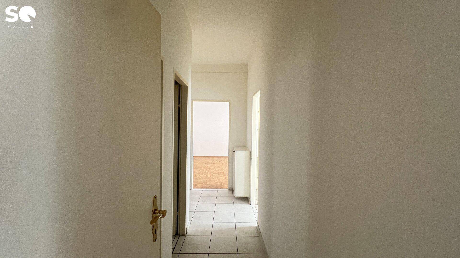 Schmaler Flur mit Fliesenboden, der verschiedene Räume der Wohnung verbindet.