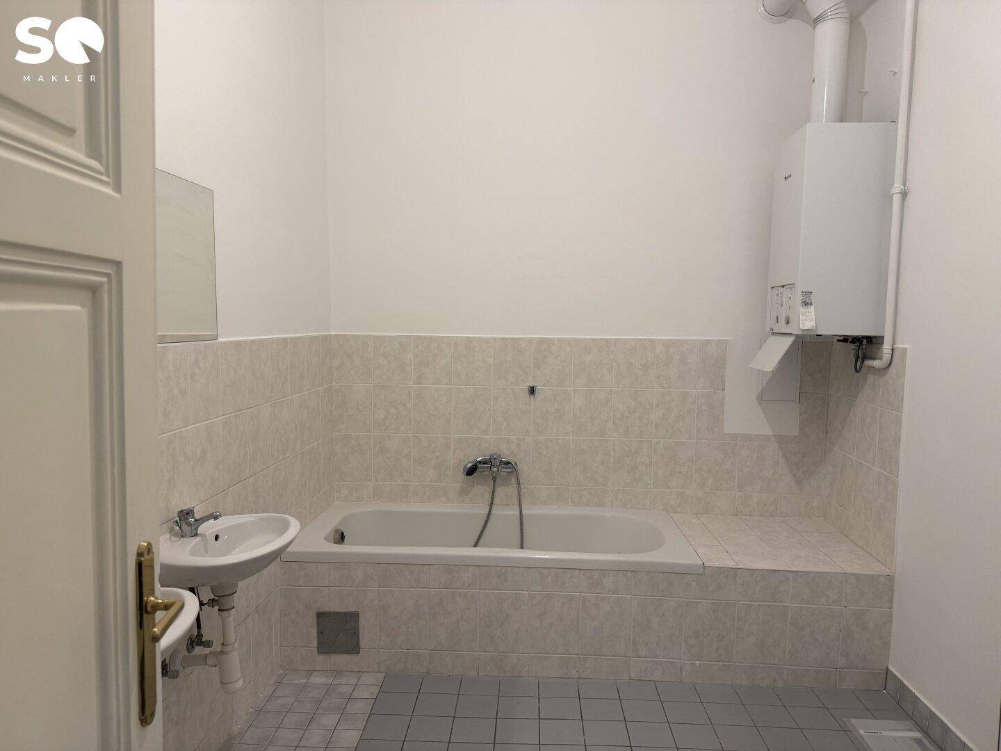 Badezimmer mit eingebauter Badewanne, Waschbecken und Wandfliesen, funktional eingerichtet.