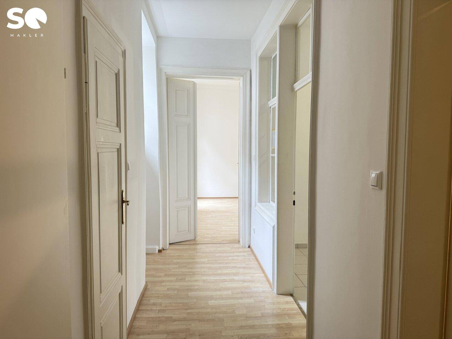 Heller Flur mit Holzboden und mehreren Türen, die zu verschiedenen Räumen führen.