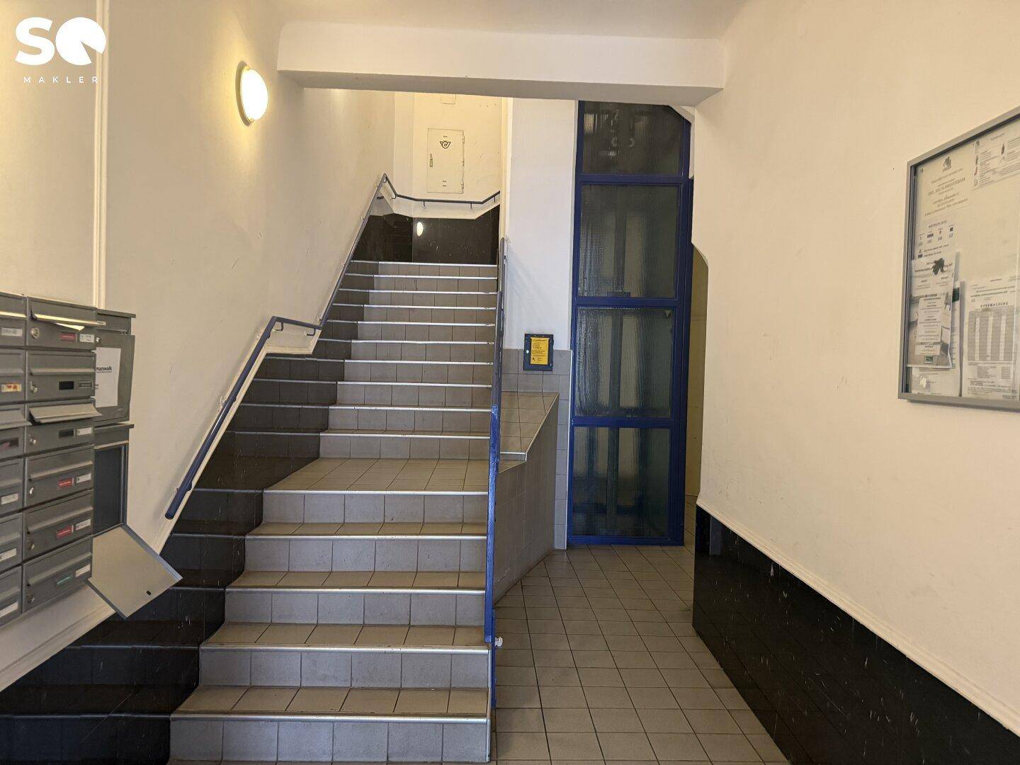 Helles Treppenhaus mit Briefkästen und Zugang zum Aufzug in einem gepflegten Mehrfamilienhaus.