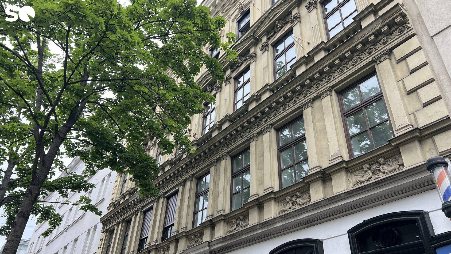 Detailansicht der reich verzierten Fassade eines Altbaus mit vielen Fenstern und Geschäften.