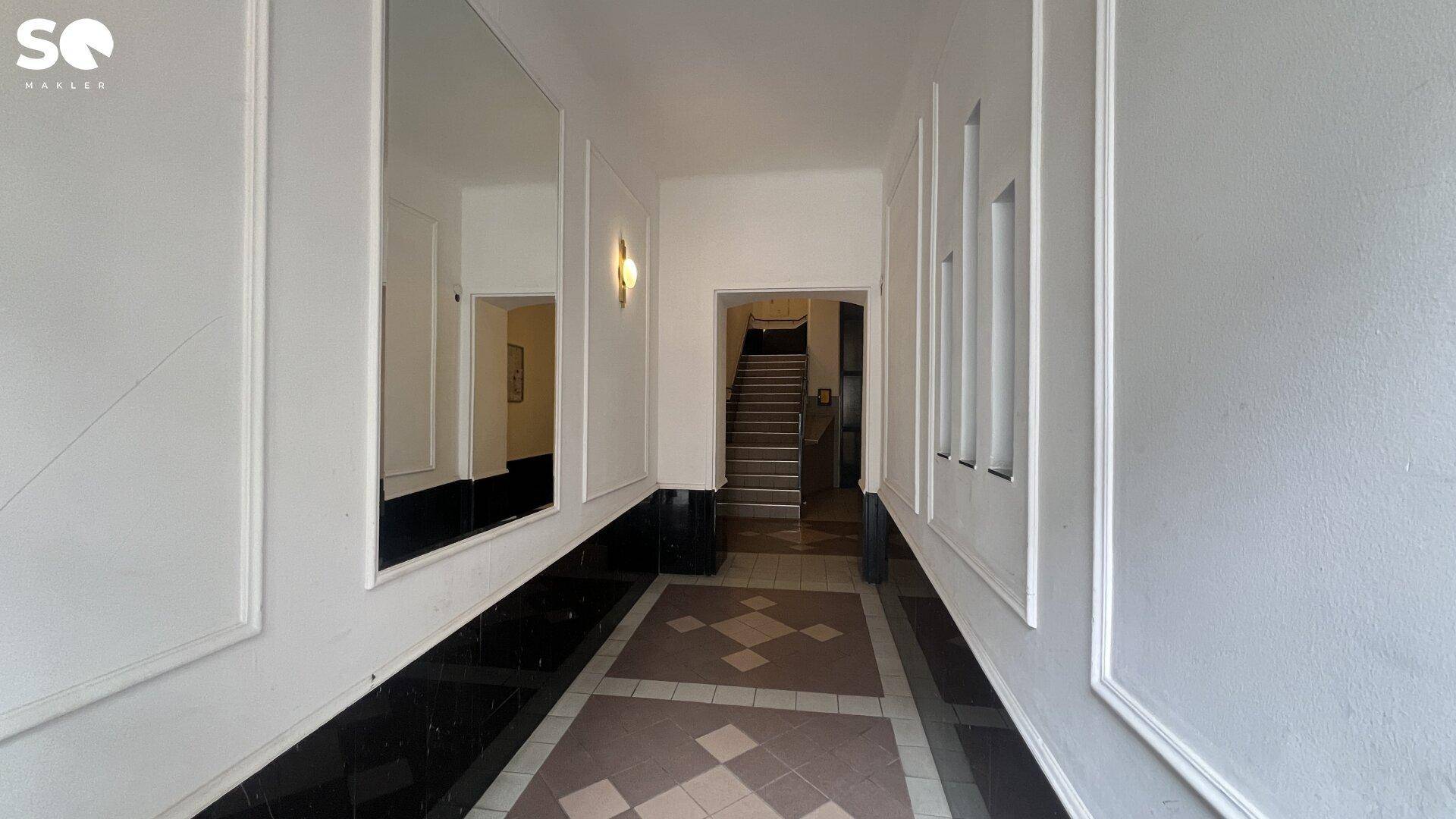 Geräumiger Flur mit klassischer Gestaltung, Fliesenboden und Zugang zum Treppenhaus in einem Altbau.