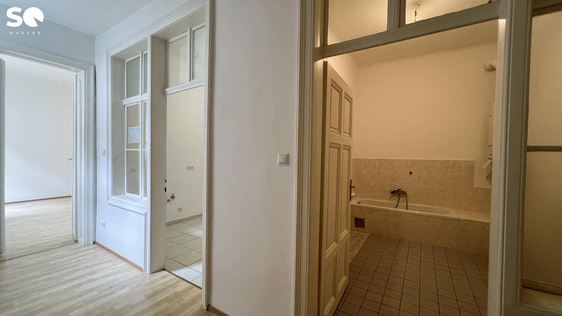 Flur mit Blick in ein Badezimmer, das eine Badewanne und Fliesenboden aufweist.