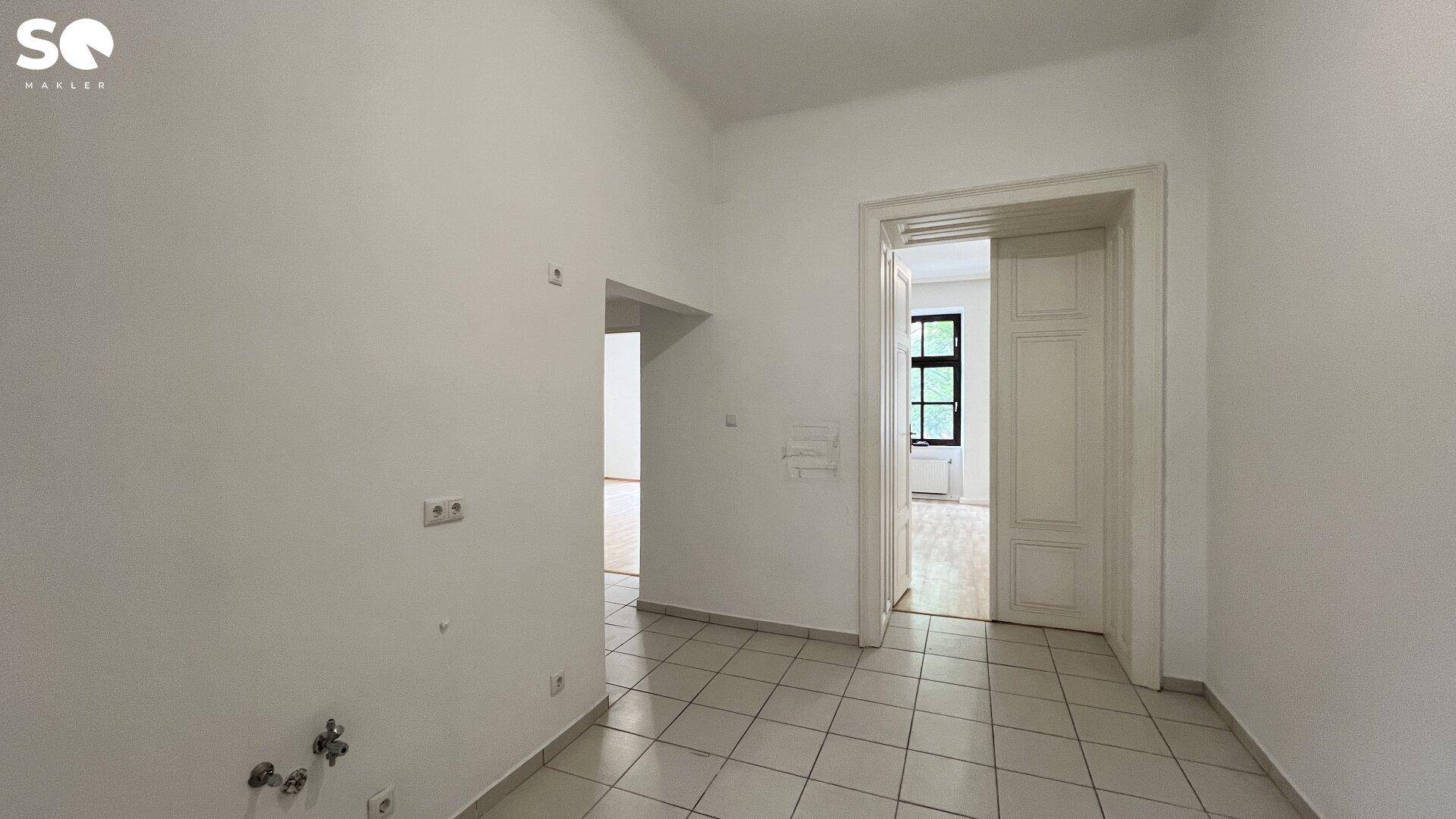 Leerer Raum mit Fliesenboden und Anschlüssen für eine Küche, bereit zur Gestaltung.