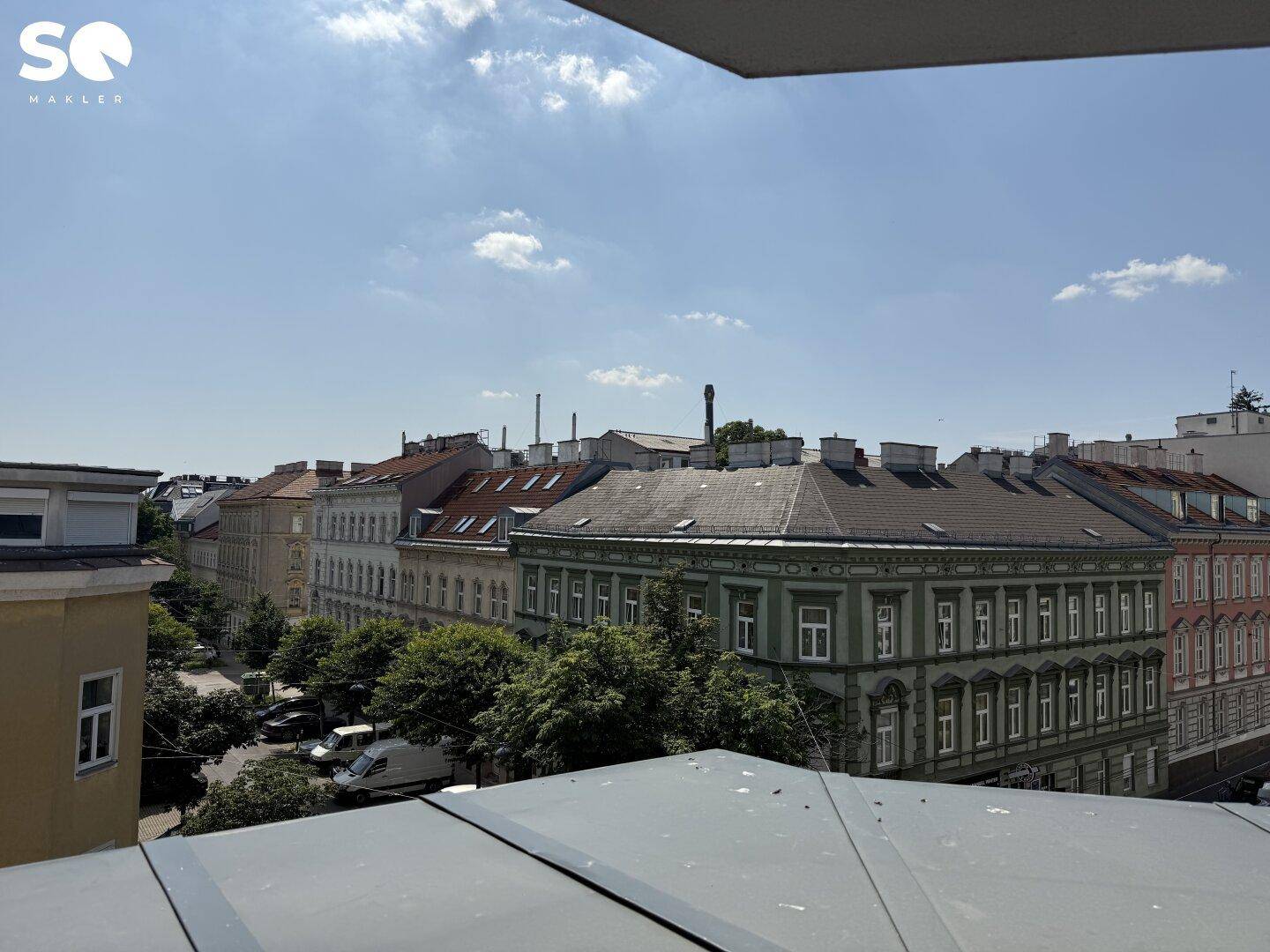 Panoramablick von einem Balkon über eine grüne Straße und die Dächer der Stadt.