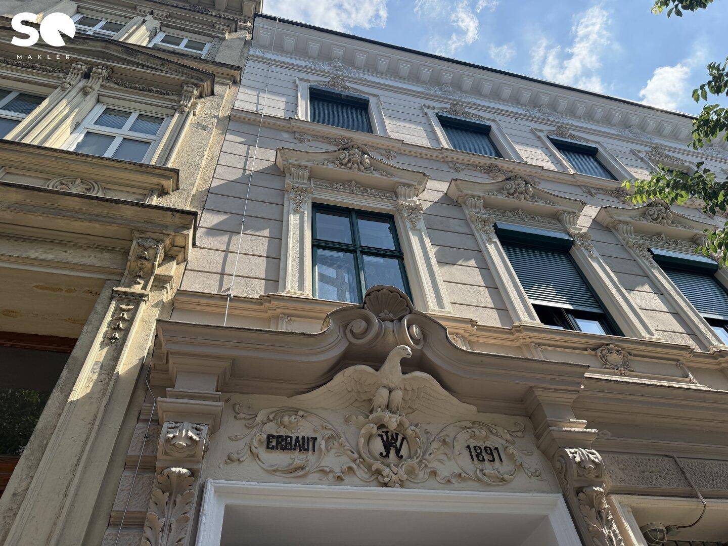 Detailansicht der historischen Fassade des Gebäudes mit aufwendigen Verzierungen und dem Baujahr 1891.