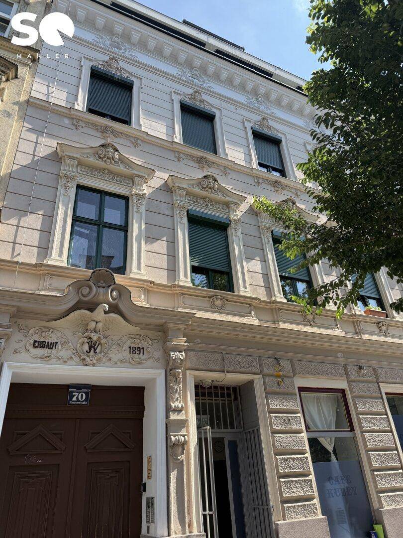 Historische Fassade des Gebäudes mit aufwendigen Verzierungen, Baujahr 1891 und Eingangsbereich.
