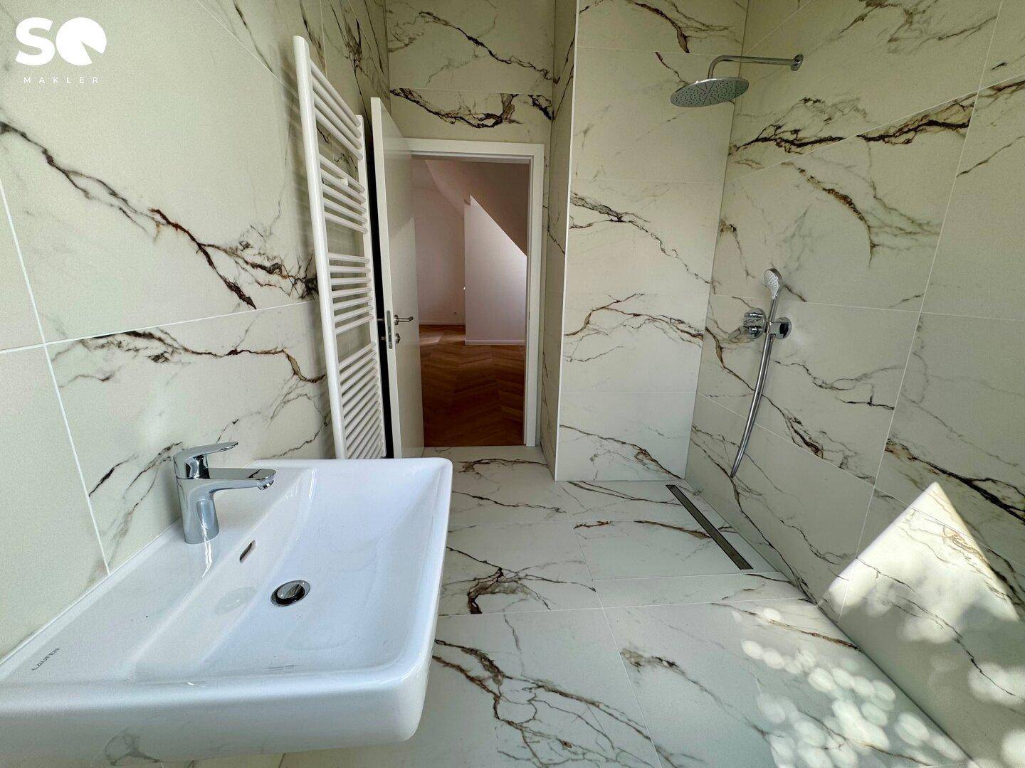 Modernes Badezimmer mit großformatigen Marmorfliesen, Dusche und einem beheizten Handtuchhalter.