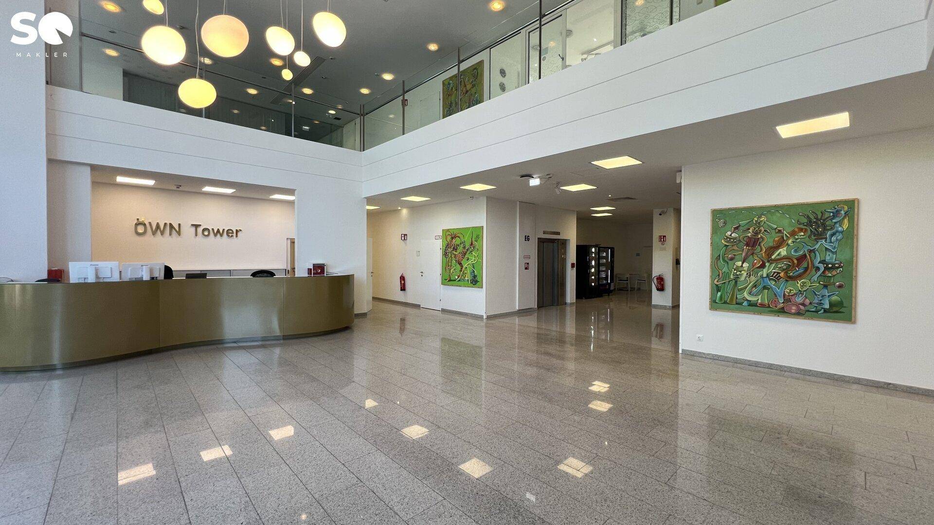 Elegante Lobby mit glänzendem Steinboden, Rezeption und modernen Kunstwerken an den Wänden.
