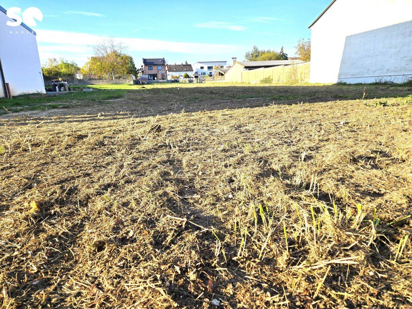 Unbebautes Grundstück mit Blick auf die Nachbarschaft und weite, offene Fläche.