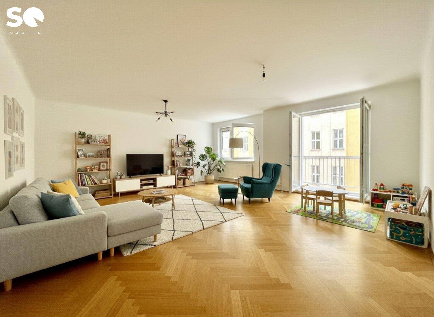 Helles Wohnzimmer mit Fischgrätparkett, moderner Einrichtung und Zugang zum Balkon.