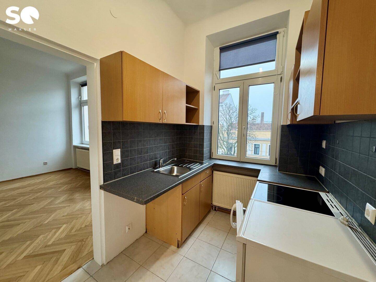 Funktionale Küche mit Holzschränken, dunkler Arbeitsplatte und Fensterblick.