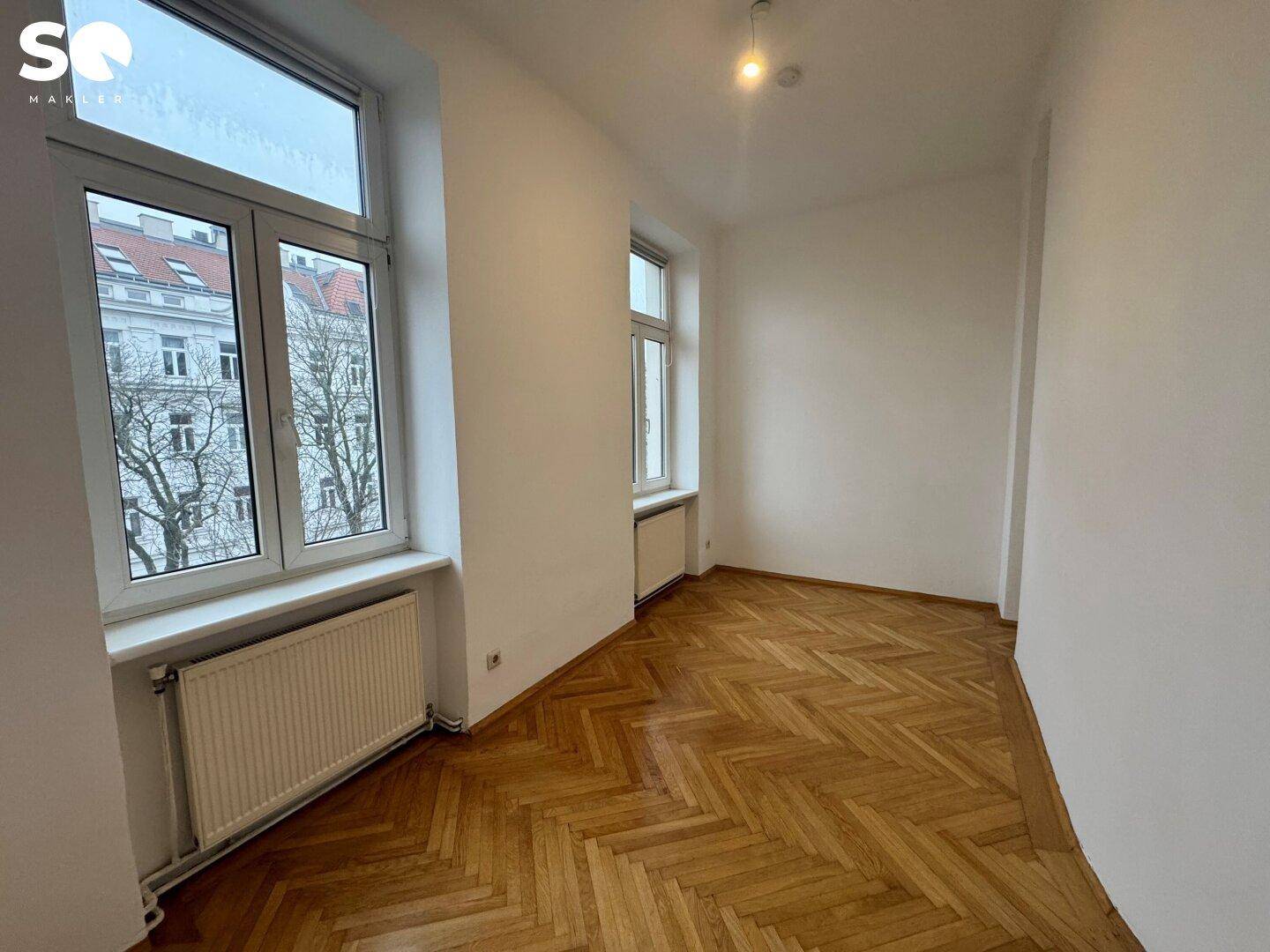 Ruhiges Zimmer mit Parkettboden und zwei Fenstern, geeignet als Schlaf- oder Arbeitszimmer.
