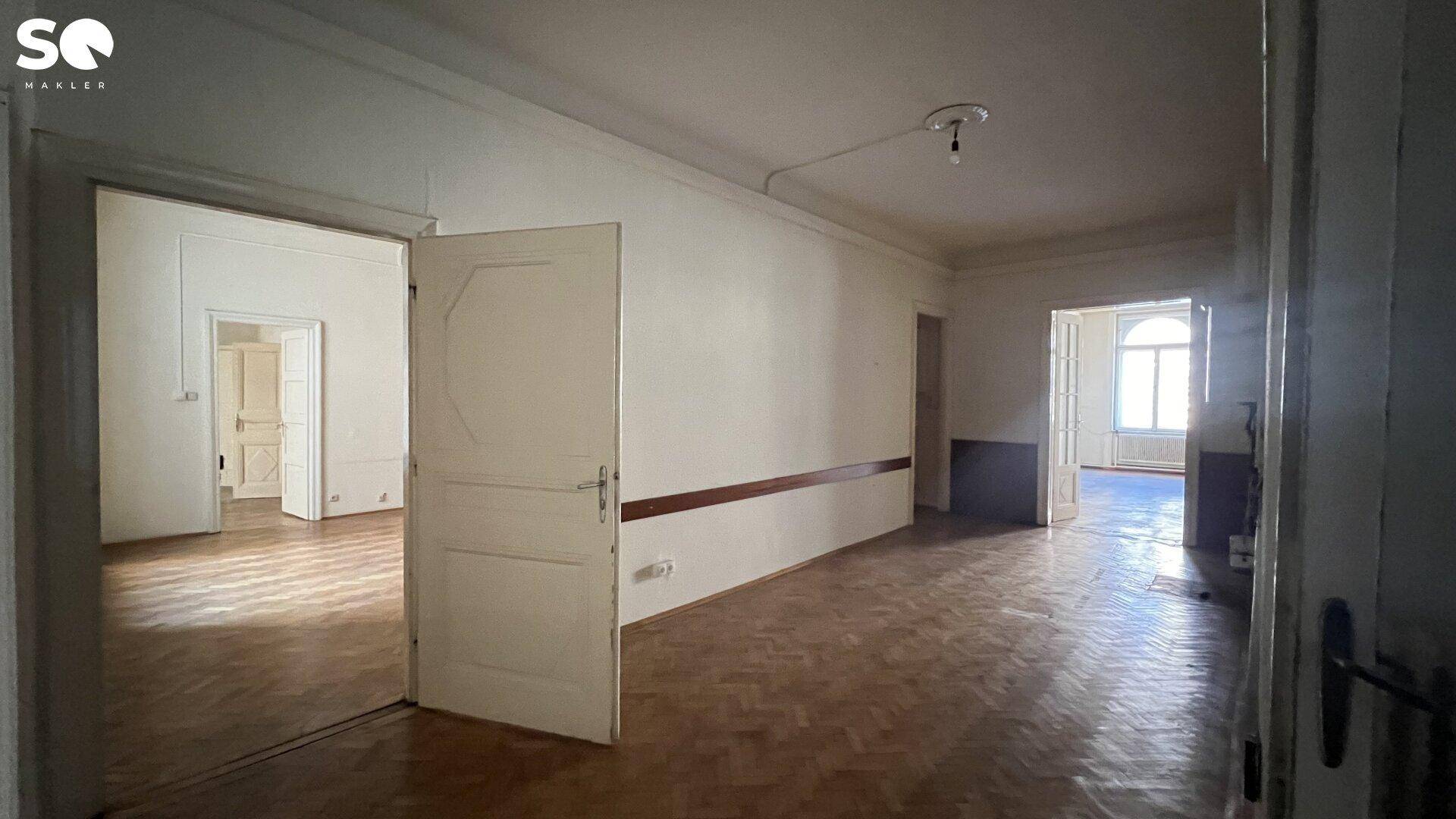 Langer Flur mit Fischgrätparkett, der mehrere Zimmer miteinander verbindet und viel Potenzial bietet.