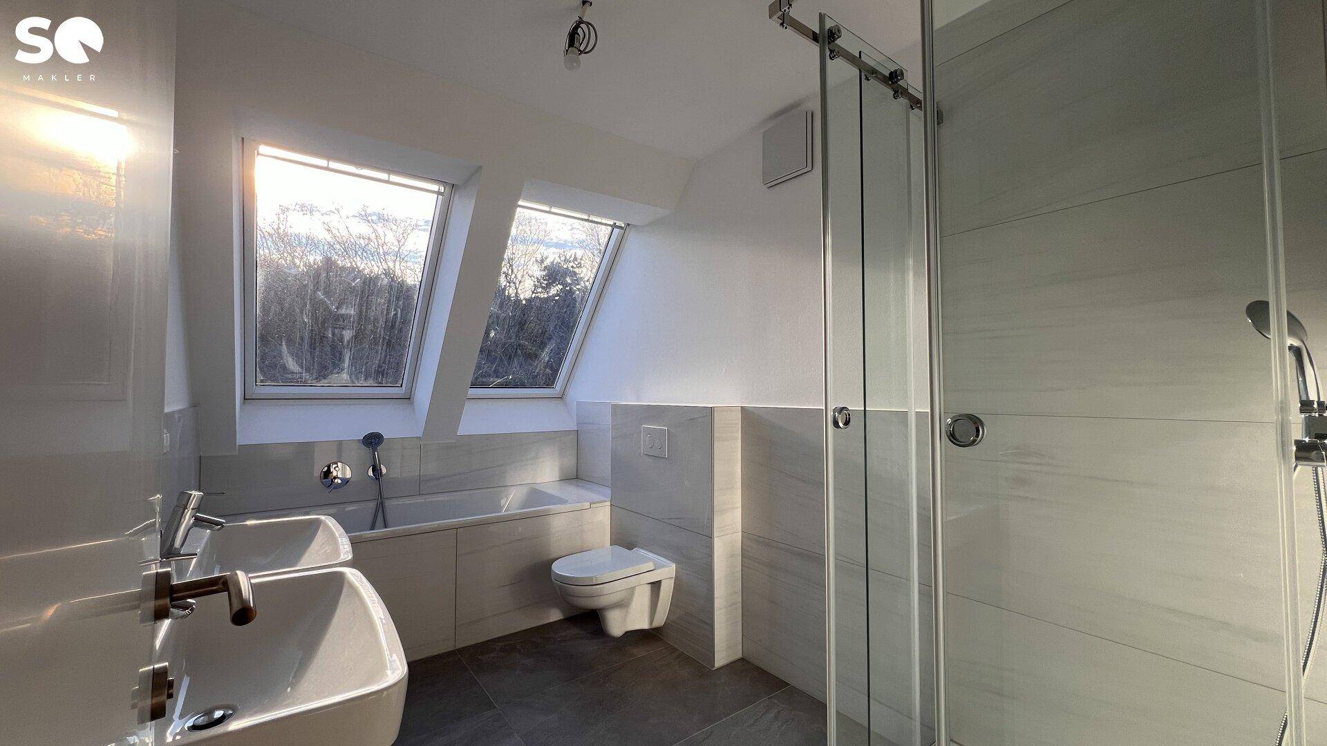 Modernes Badezimmer mit Doppelwaschbecken, Badewanne unter Dachfenstern und einer geräumigen begehbaren Dusche.