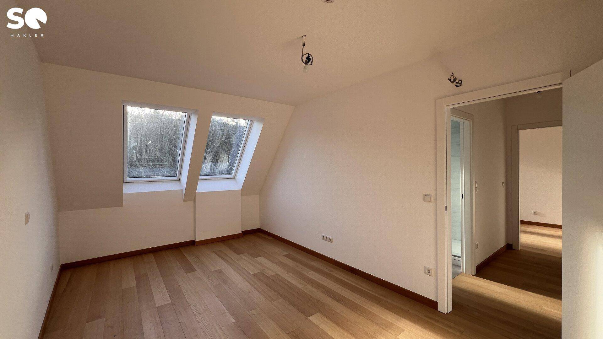Geräumiges Zimmer mit Holzboden, weißen Wänden und Dachschrägen, ideal als Schlaf- oder Arbeitszimmer.